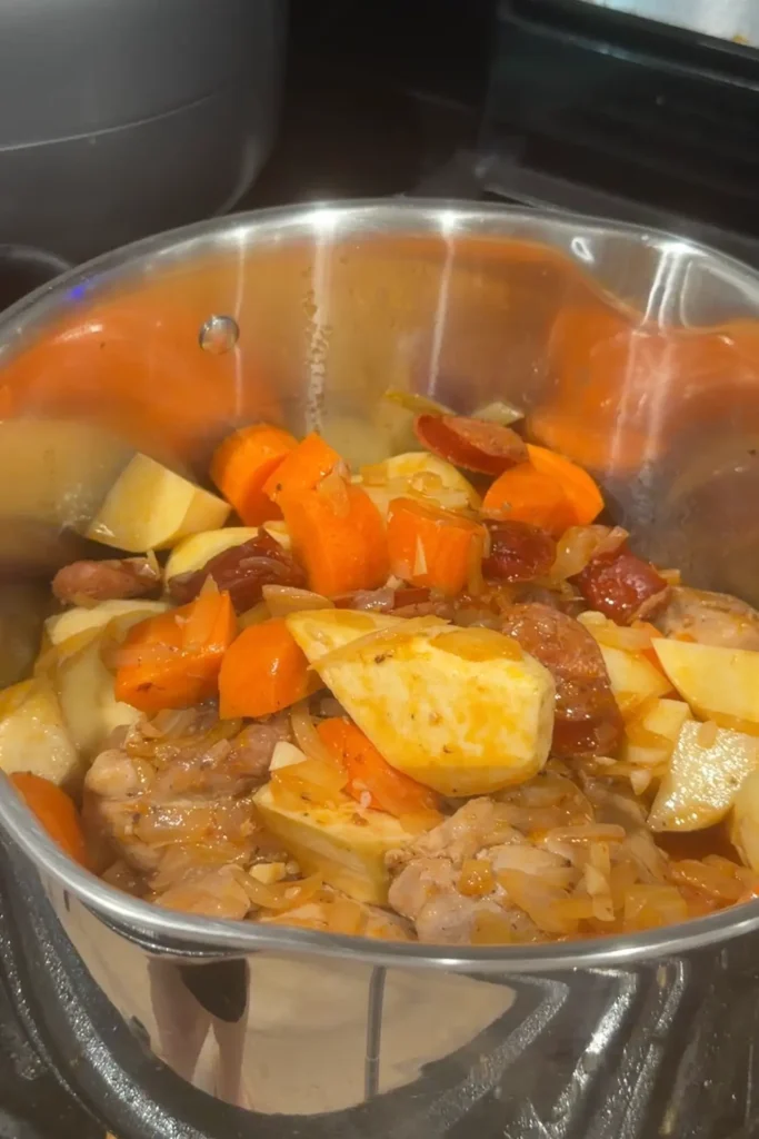 Chicken pochero simmering with potatoes, carrots, and Chorizo de Bilbao