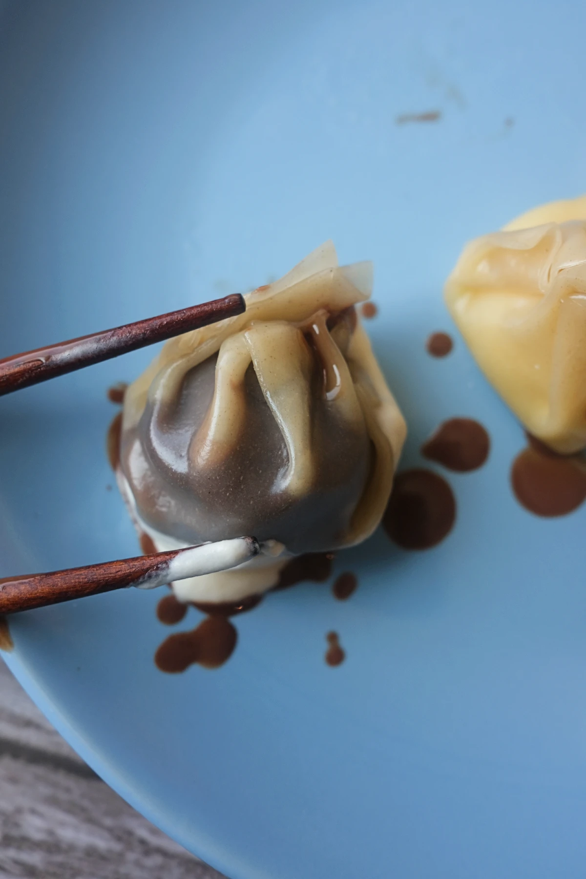 Steamed chocolate dumpling served with salted caramel cream on a blue plate.
