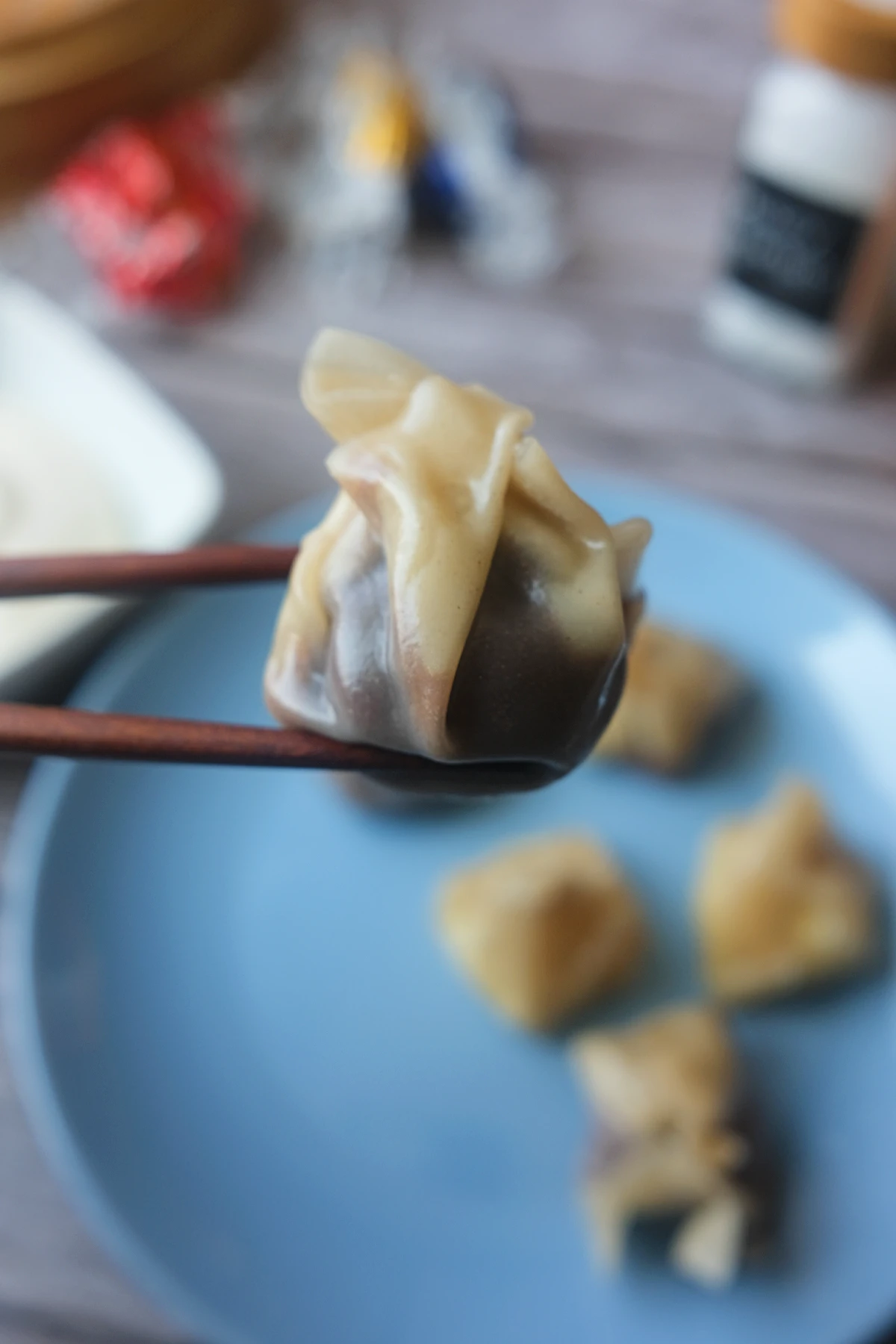 Chopsticks holding a freshly steamed chocolate dumpling made with a wonton wrapper and melted chocolate filling.
