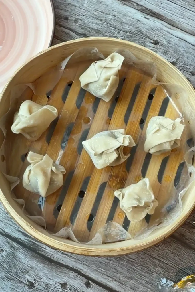 Uncooked chocolate dumplings arranged in a parchment-lined bamboo steamer basket, ready to be steamed.