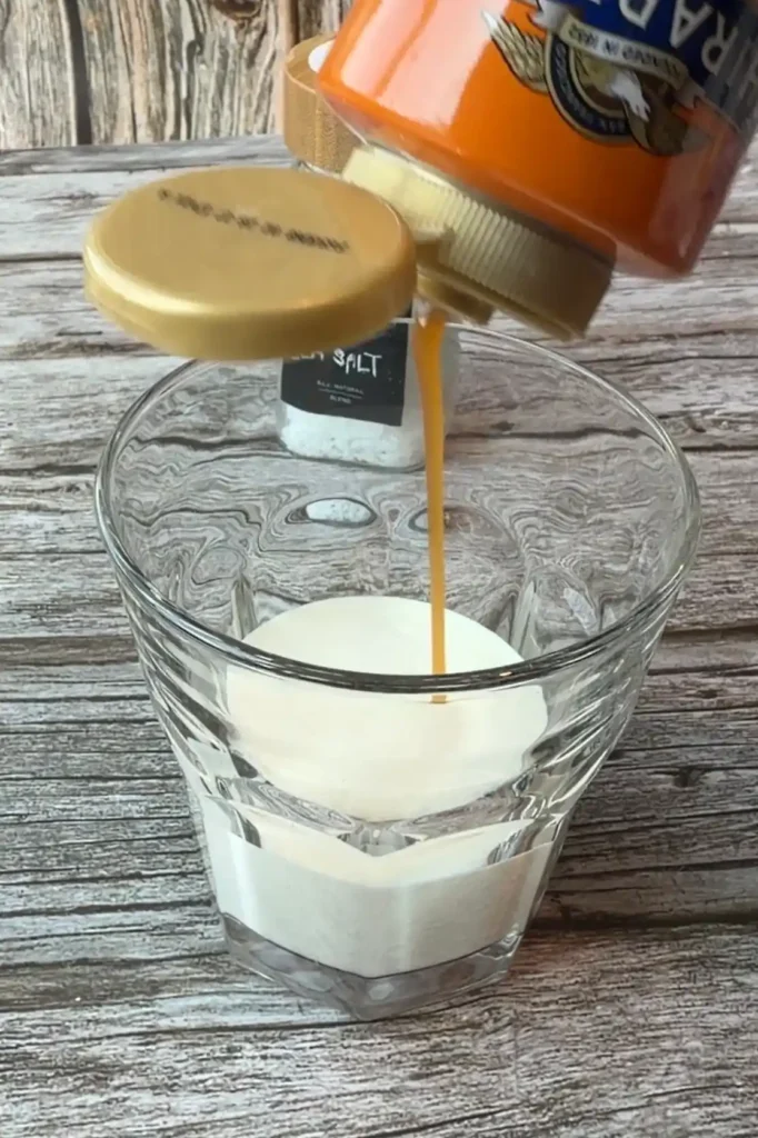 Caramel sauce being added to heavy whipping cream before whipping into a fluffy salted caramel cream.