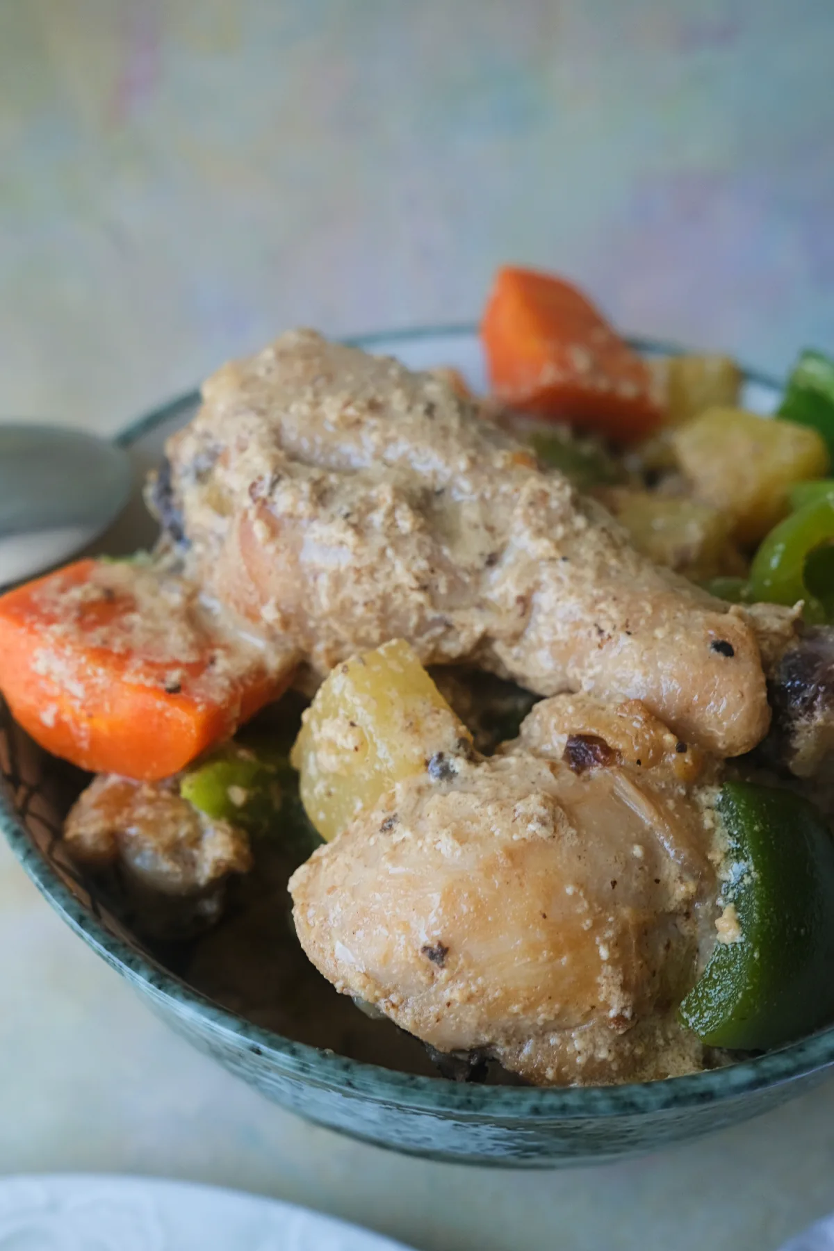 Bowl of creamy Pininyahang Manok with chicken, pineapple chunks, carrots, and green bell peppers.