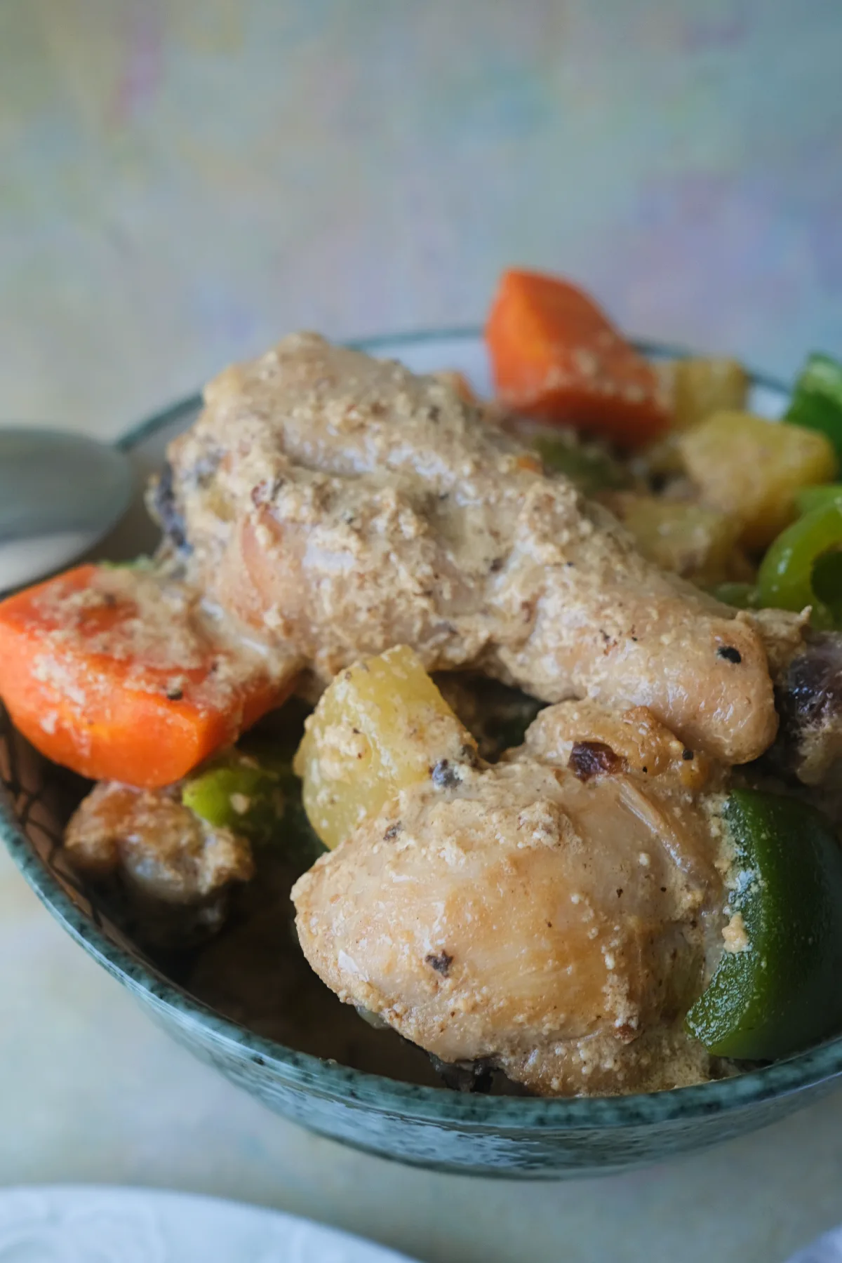 Bowl of creamy Pininyahang Manok with chicken, pineapple chunks, carrots, and green bell peppers.