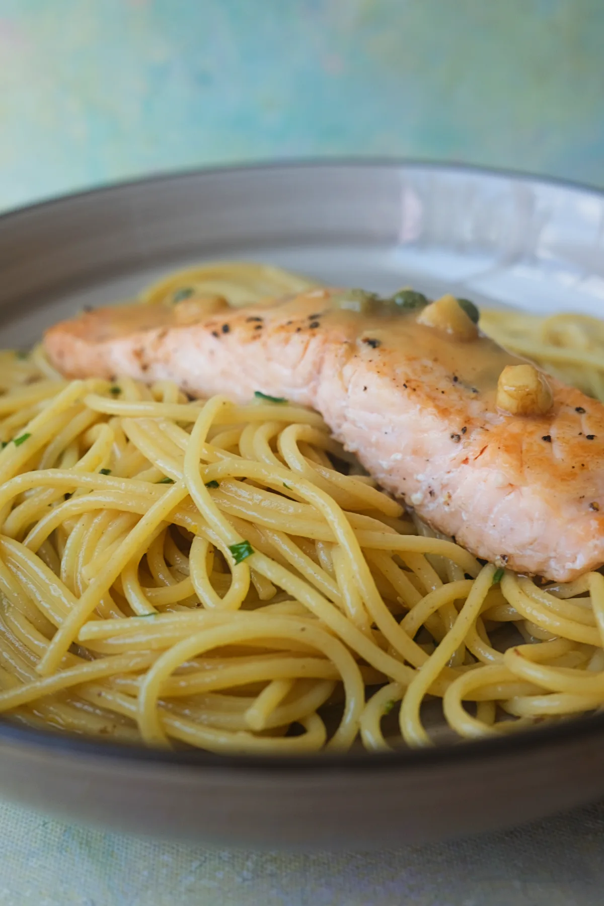 Pan-seared salmon fillets topped with lemon caper sauce and served over spaghetti.