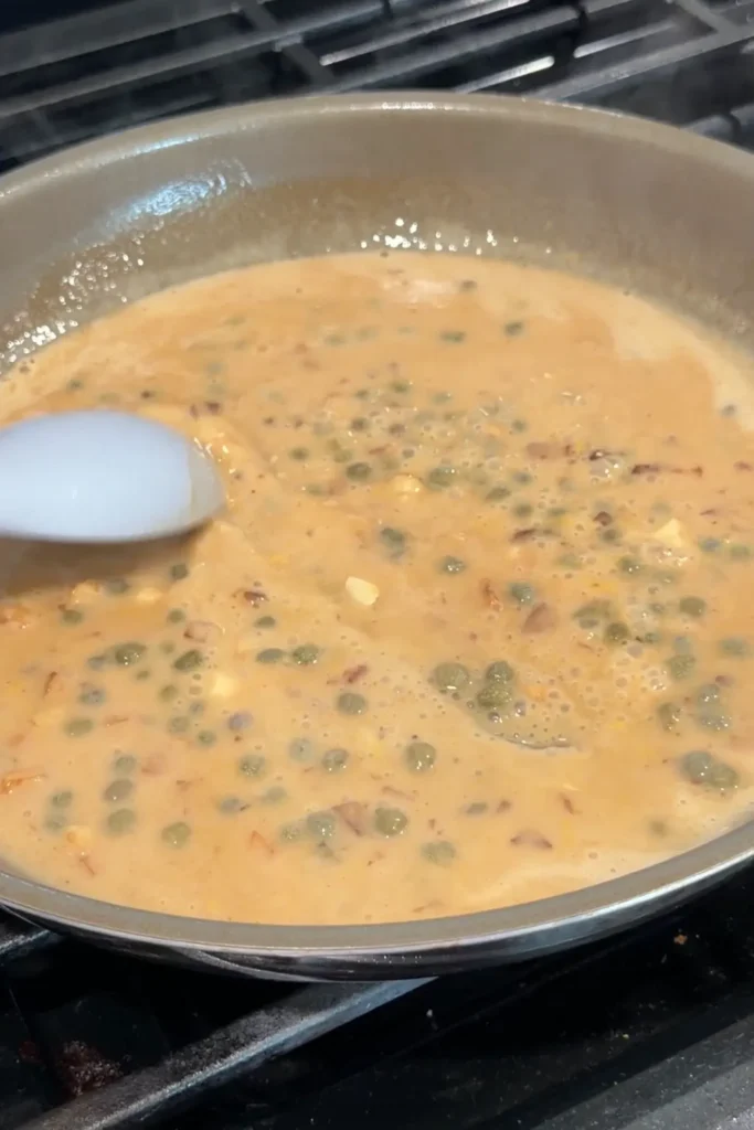 Lemon caper sauce simmering in a skillet until slightly thickened.
