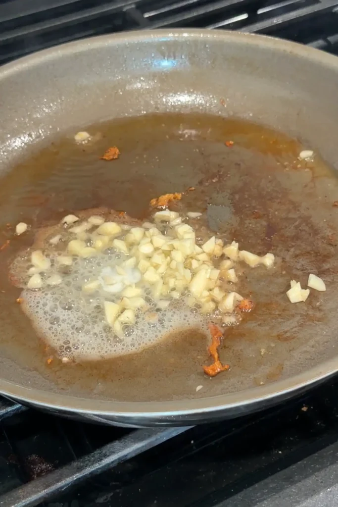 Chopped garlic sautéing in butter and pan drippings.