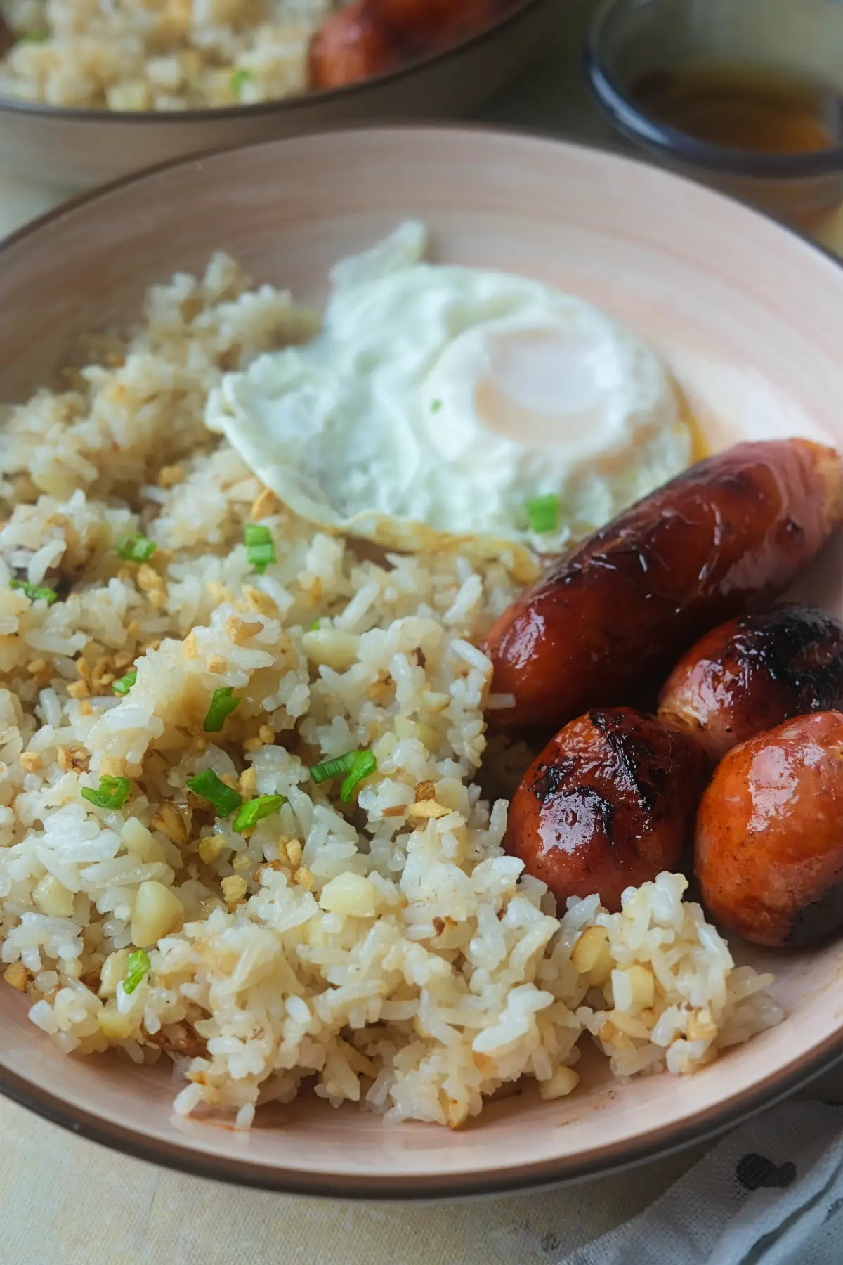 Close-up of longsilog with garlic fried rice, fried egg, and caramelized Filipino longganisa