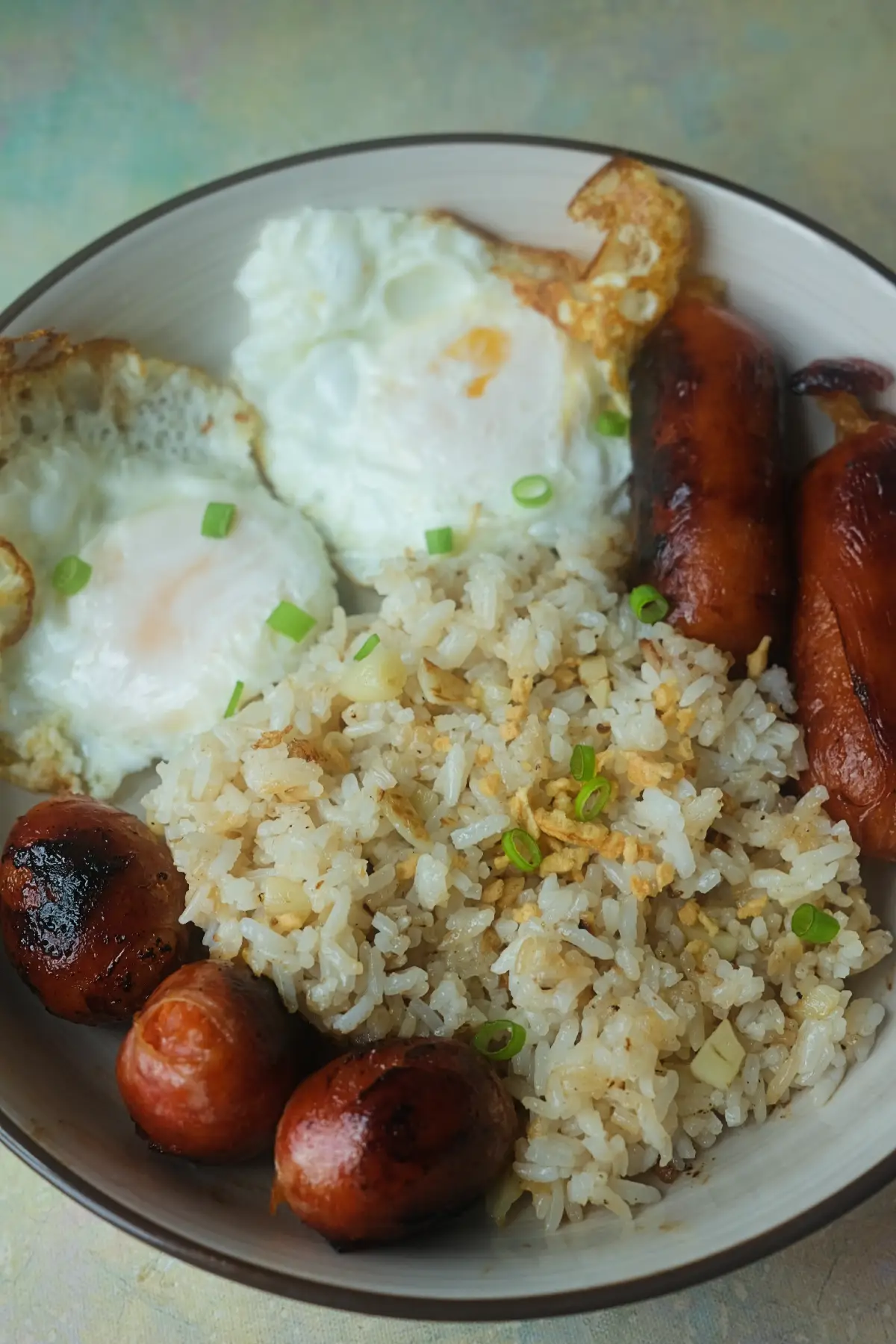 Filipino longsilog breakfast with sinangag, two fried eggs, and longganisa