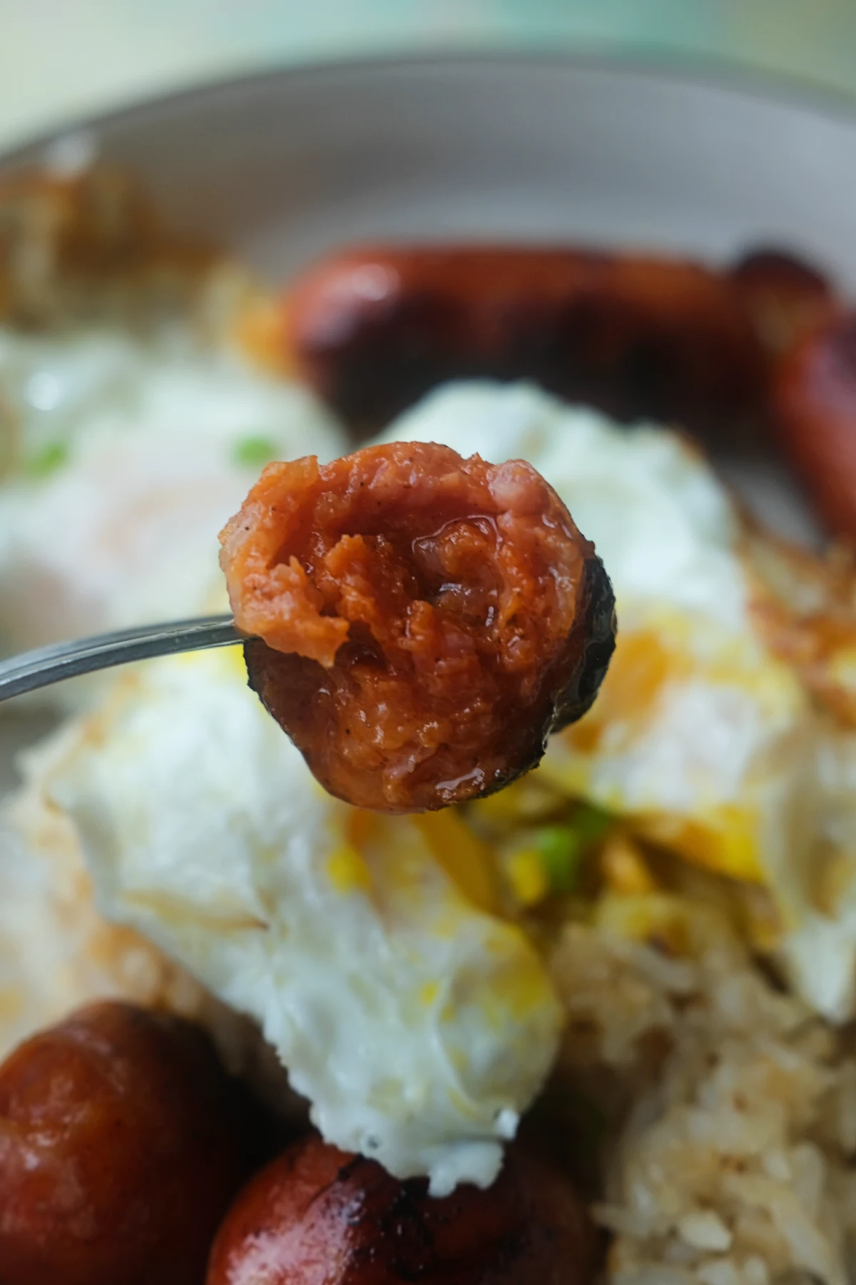 Close-up of sliced Filipino longganisa served with fried eggs and garlic rice