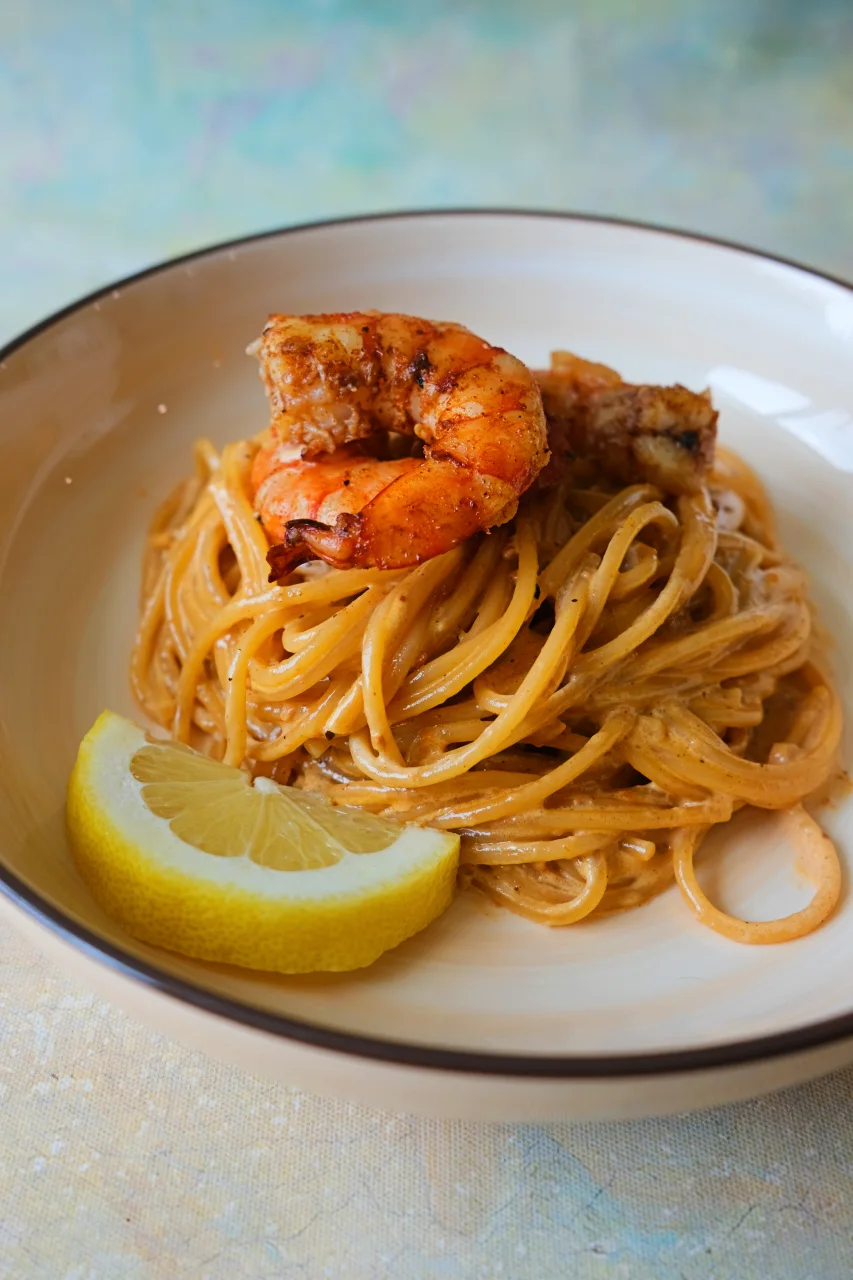 crab paste pasta topped with seasoned shrimp and served with a lemon wedge.