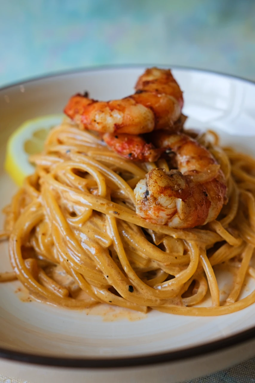 Creamy crab paste pasta topped with seasoned shrimp and served with a lemon wedge.