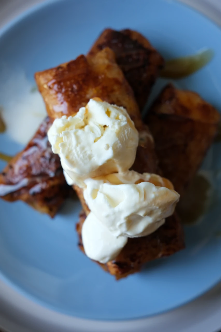 Overhead view of apple turon à la mode with vanilla ice cream on a blue plate.