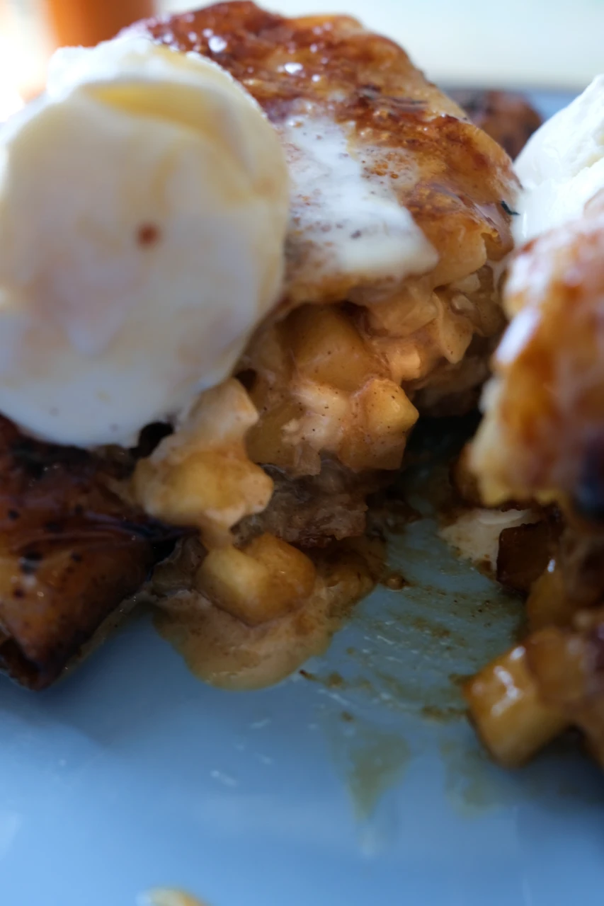 Close-up of apple pie turon with cinnamon apple filling, vanilla ice cream, and caramel sauce.