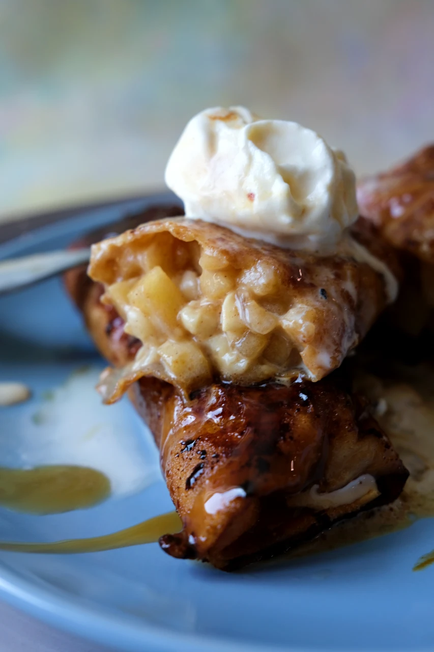 Cut-open apple turon showing the buttery cinnamon apple filling with vanilla ice cream on top.