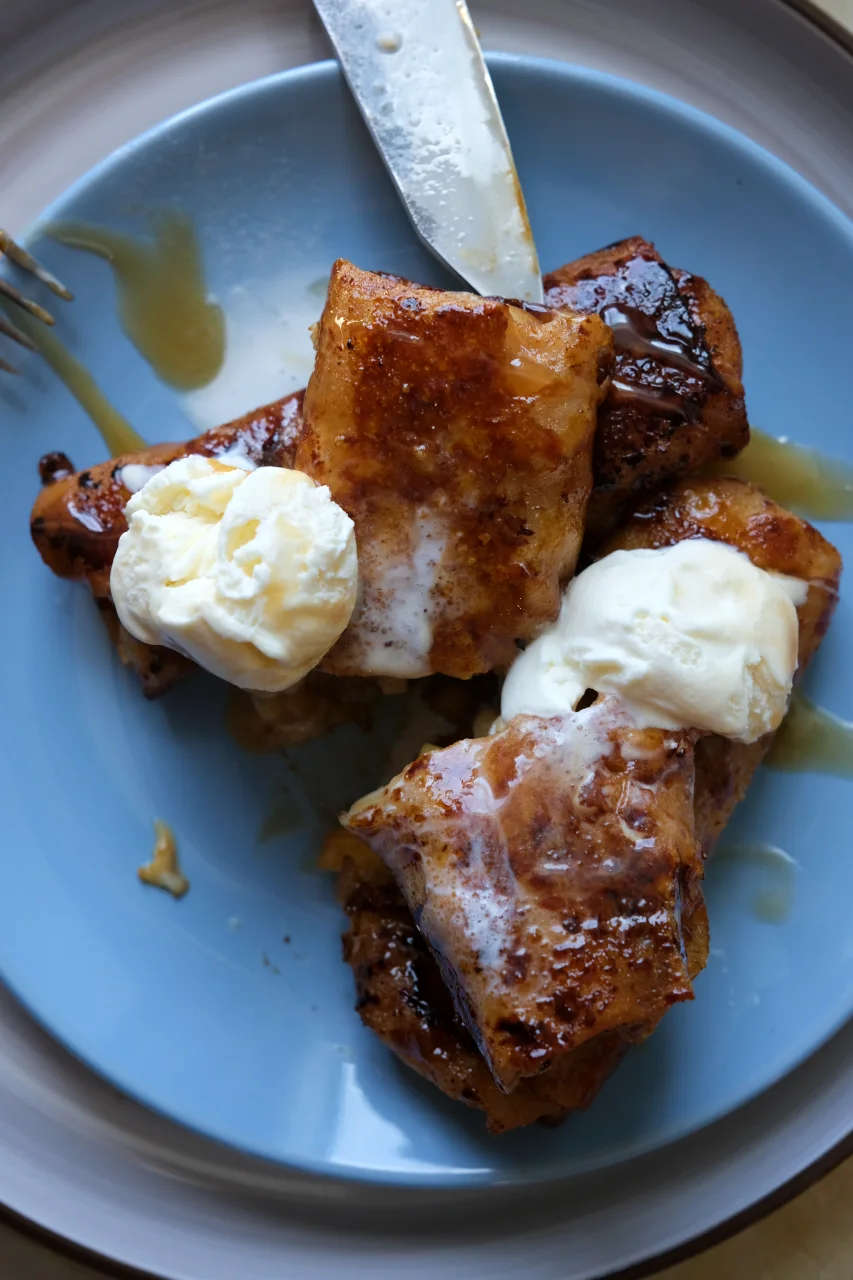 Overhead view of crispy caramelized apple turon served with vanilla ice cream and caramel sauce.