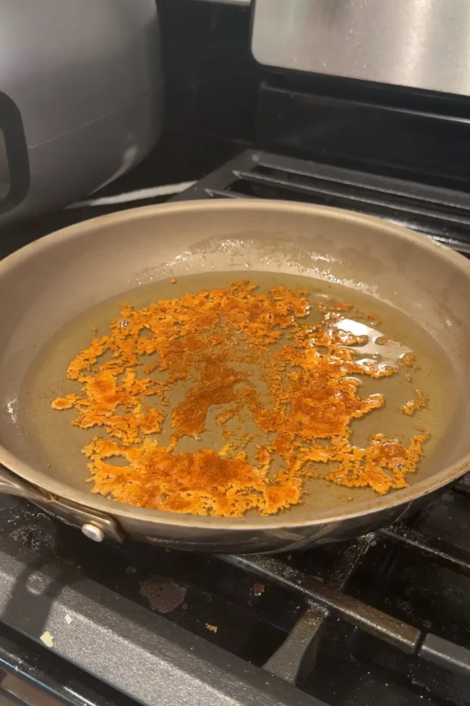 Brown sugar floating and caramelizing in hot oil before frying the apple turon.