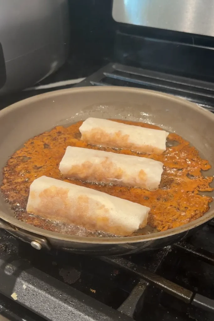 Apple turon frying in hot oil with caramelized brown sugar.