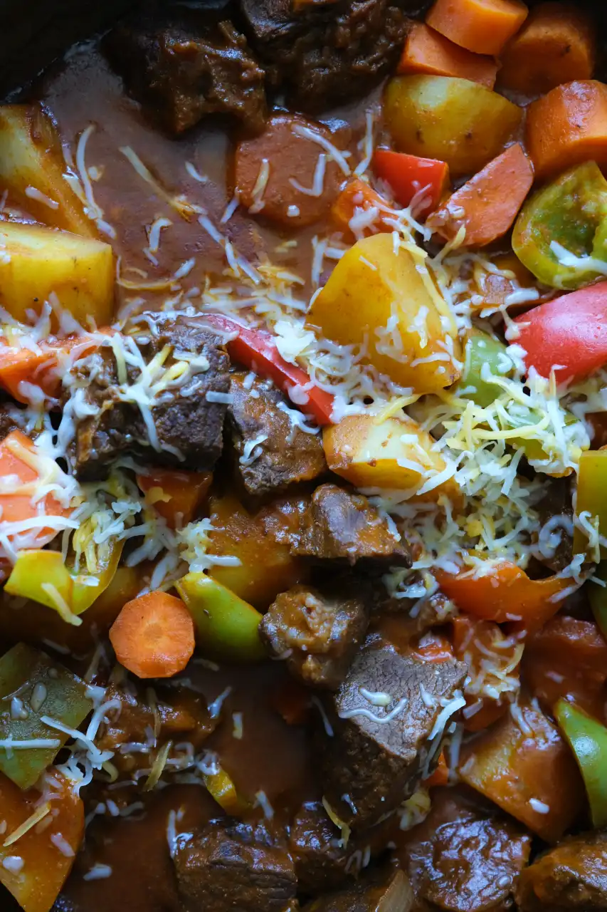 Close-up of Filipino beef kaldereta with tender beef, vegetables, and shredded cheese.