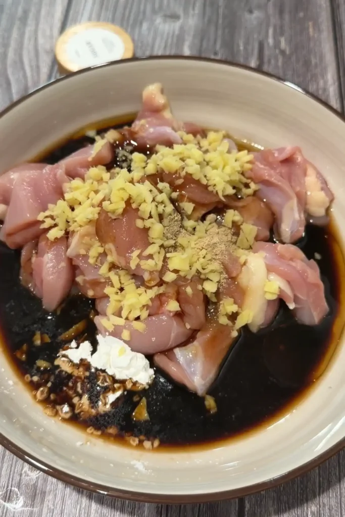 Raw chicken thighs with soy sauce, oyster sauce, ginger, white pepper, and cornstarch for claypot chicken rice.