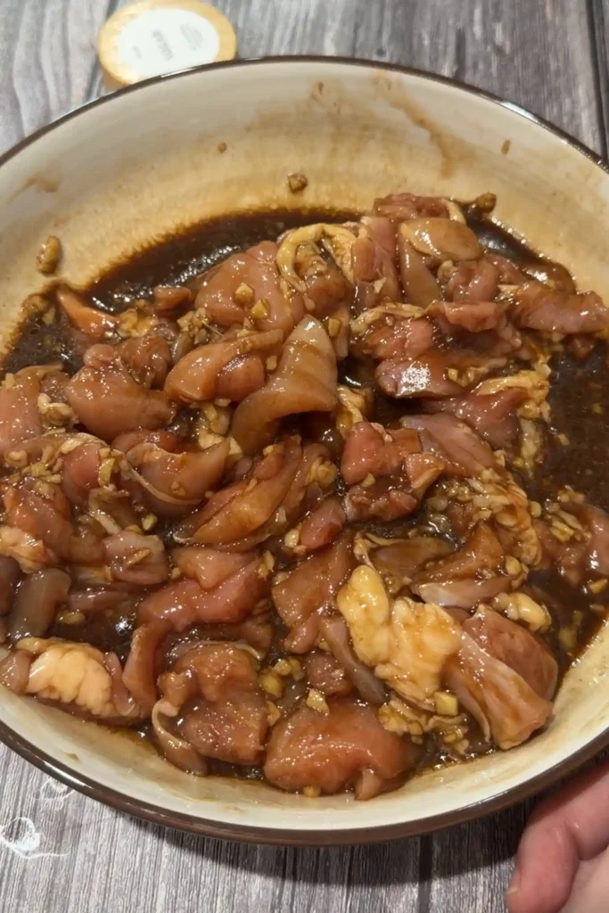 Chicken thigh pieces coated in the soy-based marinade for rice cooker claypot chicken rice.