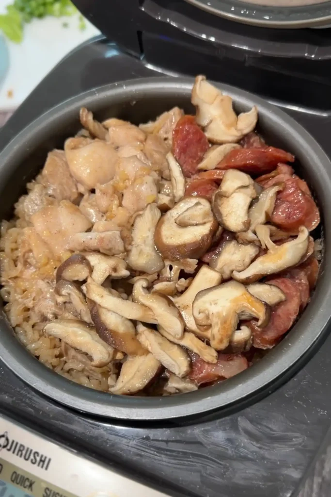 Cooked rice cooker claypot chicken rice with chicken thighs, Chinese sausage, and shiitake mushrooms.