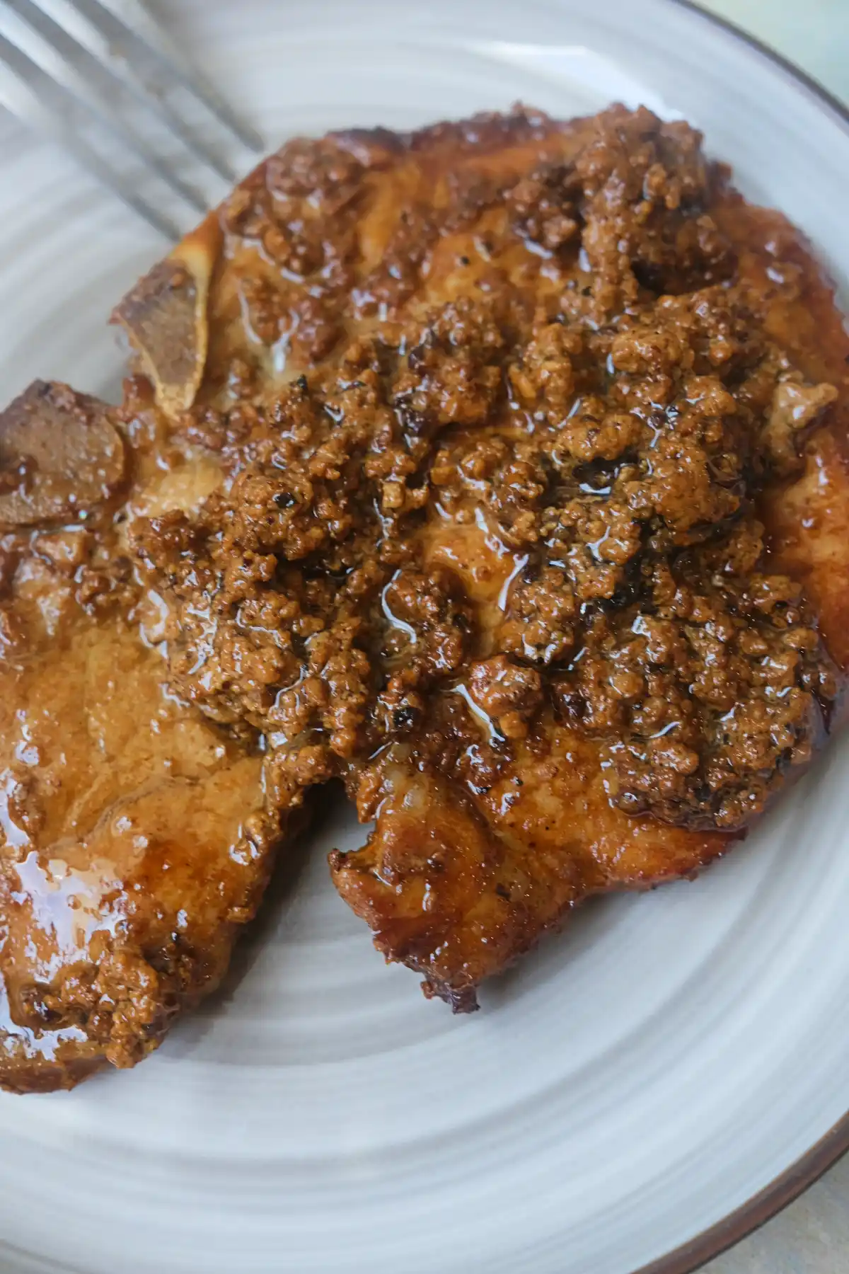 Close-up of a creamy pork chop topped with browned milk curds.