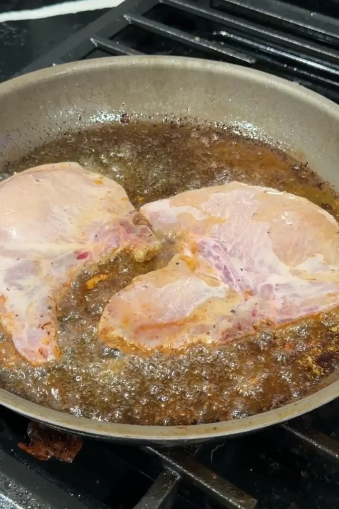 Pork chops browning in butter in a large skillet.
