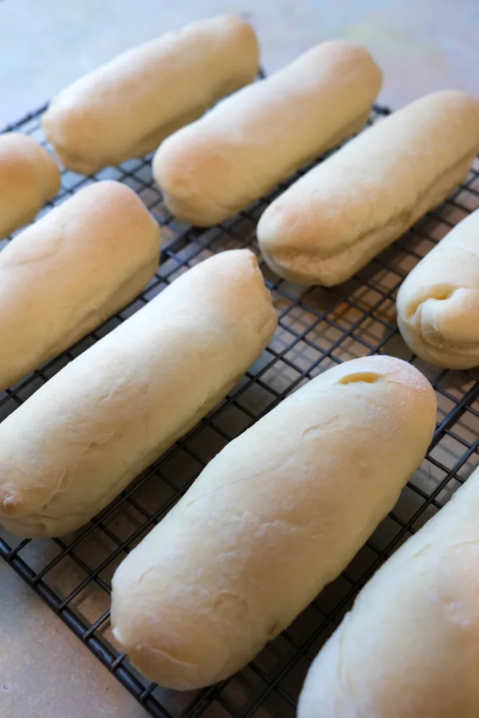 Freshly baked Filipino cheese rolls cooling on a wire rack.