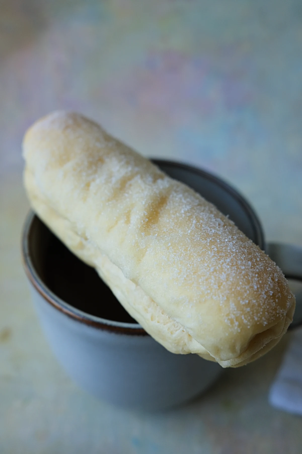 Filipino cheese roll with a buttery sugar topping served over a cup of hot chocolate.