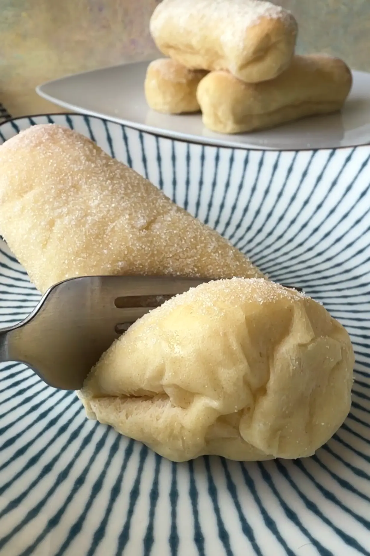 Fork pressing into a soft, pillowy Filipino cheese roll with a sugar topping.