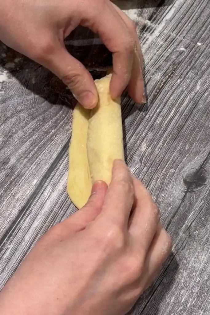 Folding cheese roll dough over a strip of cheese to enclose the filling.