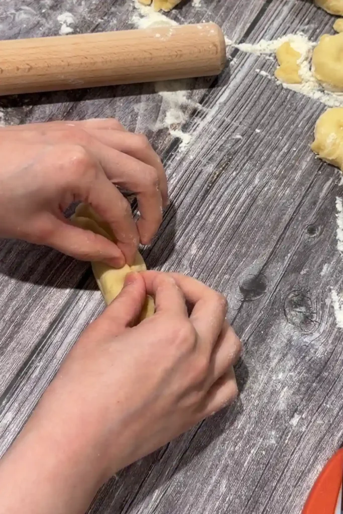 Pinching the seam of a cheese-filled bread roll closed before baking.