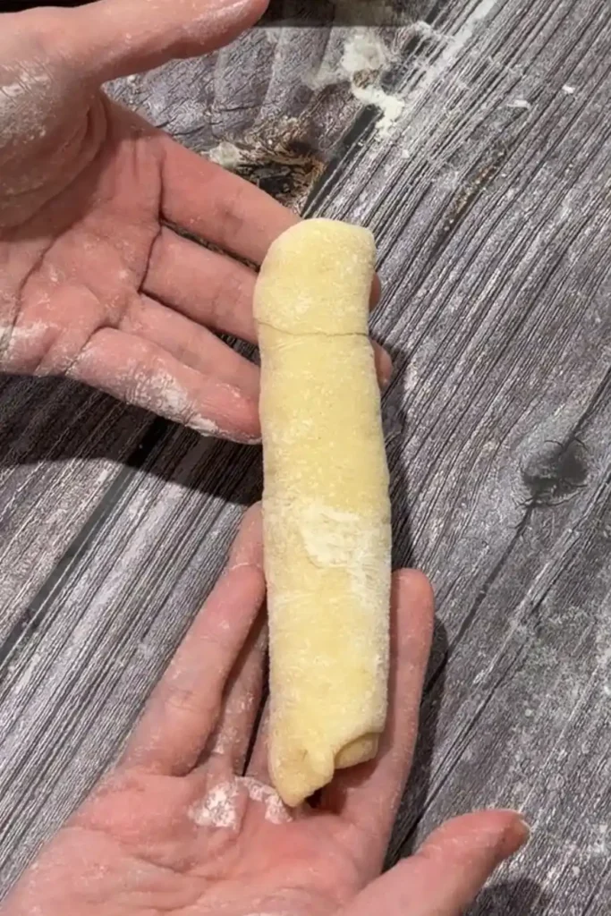 Shaped Filipino cheese roll held in both hands before proofing.