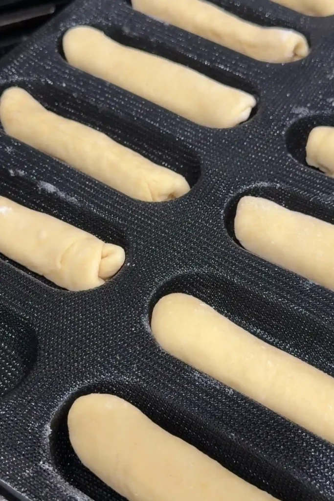 Shaped cheese rolls arranged in a baking pan before the second rise.