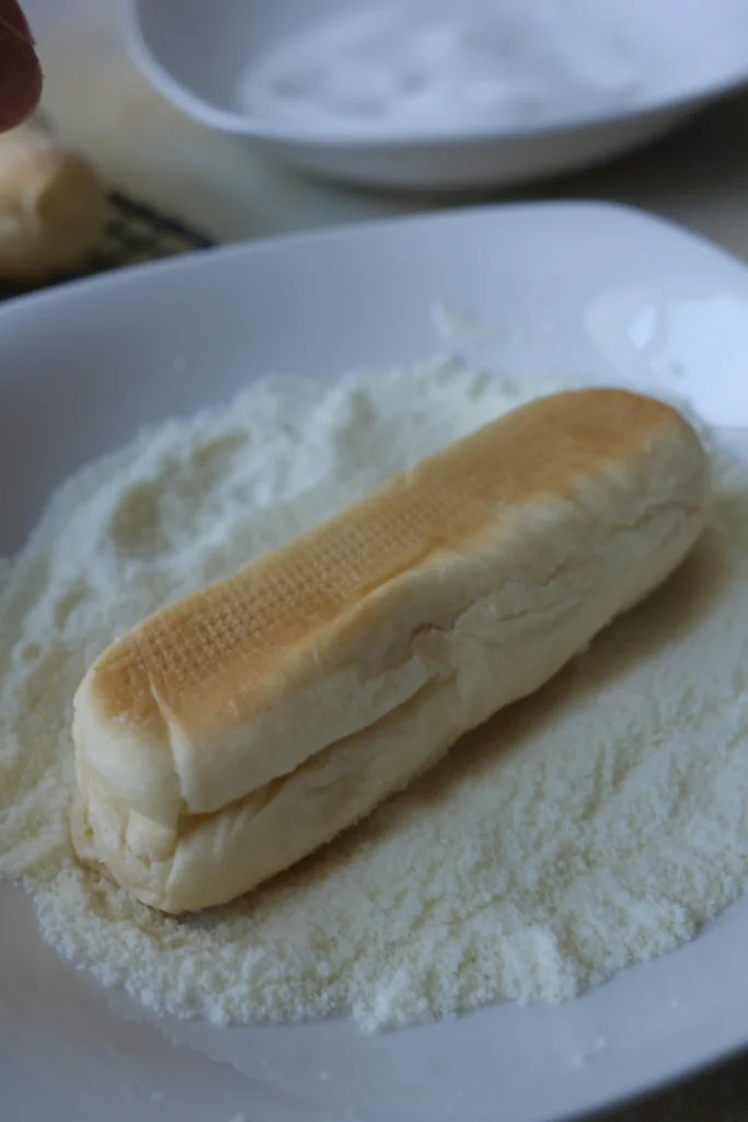 Filipino cheese roll coated generously in powdered milk after baking.