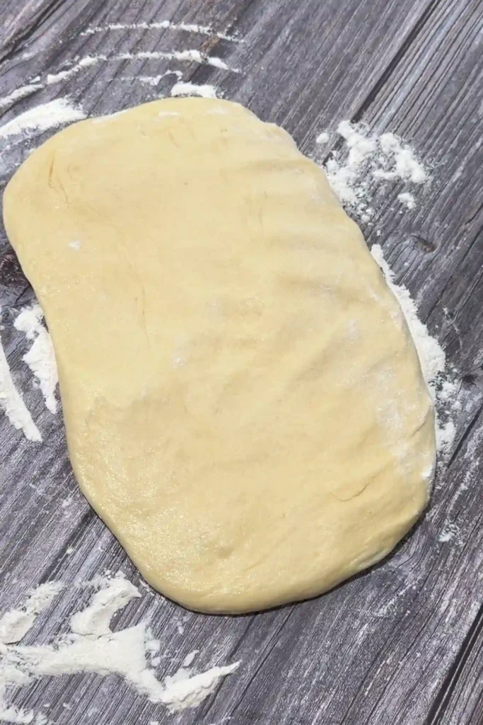 Filipino cheese roll dough flattened into a rectangle on a lightly floured work surface.