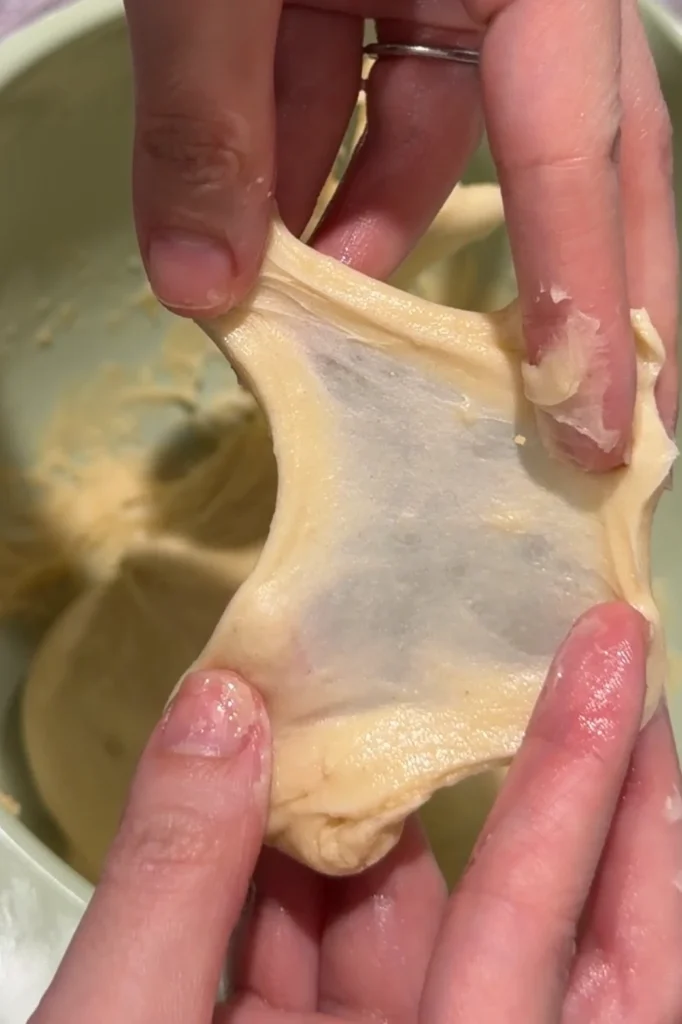 Stretching cheese roll dough to check for a thin, translucent windowpane.