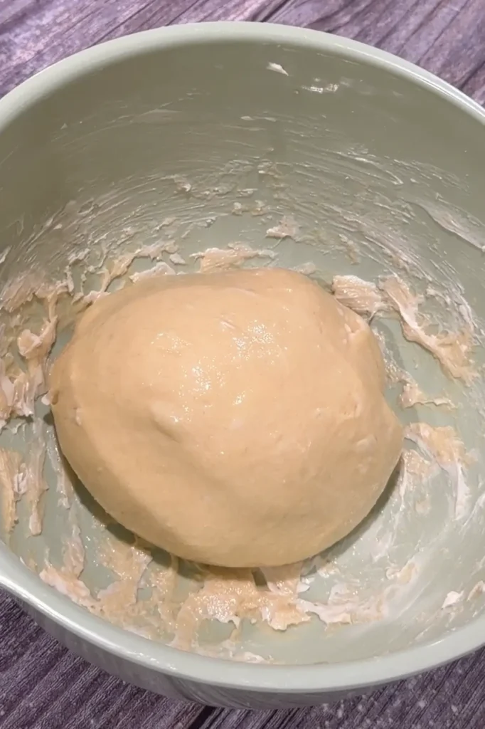 Smooth cheese roll dough resting in a bowl before the first rise.