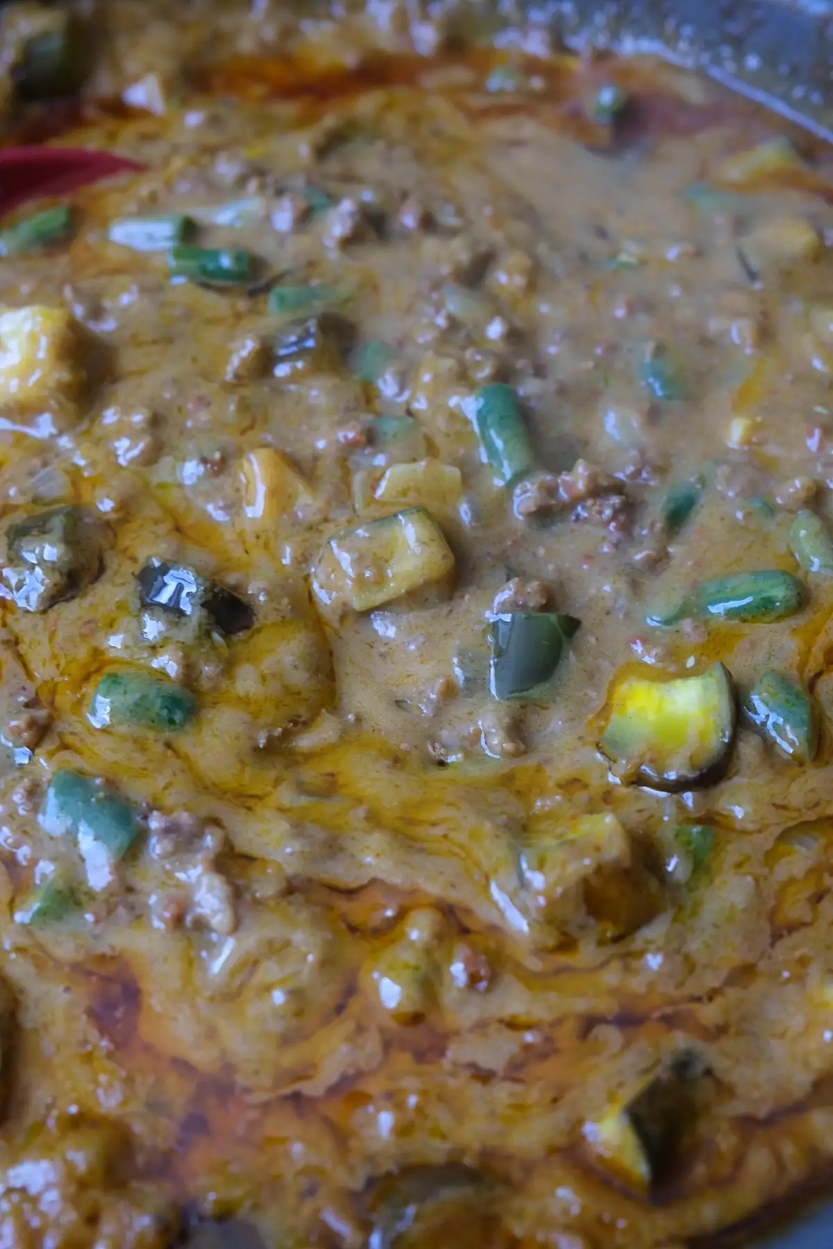 Close-up of creamy peanut sauce with ground beef, eggplant, and long beans.