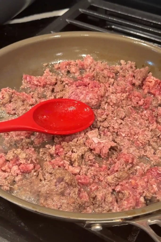 Ground beef browning in a skillet for easy ground beef kare kare.