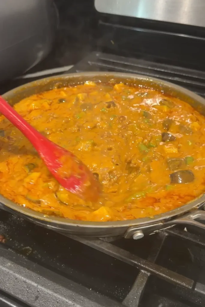 Ground beef kare kare simmering with eggplant and long beans in peanut sauce.