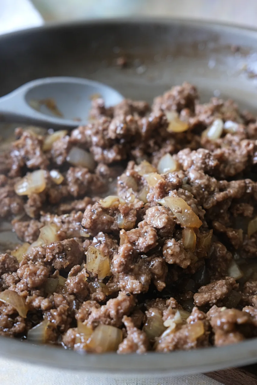 Close-up of honey ground beef and sautéed onions in a skillet.