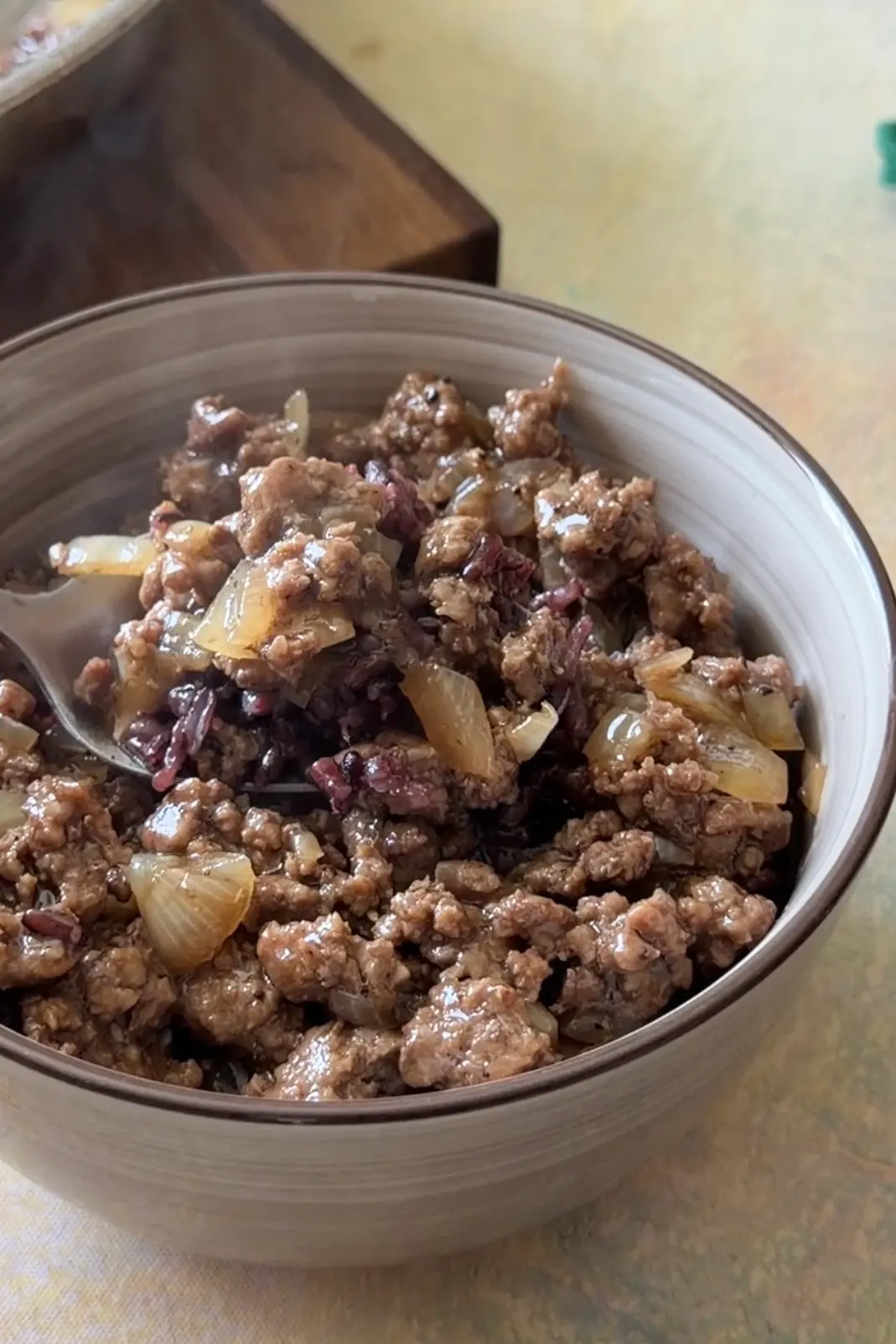 Honey ground beef and onions served over rice in a bowl.