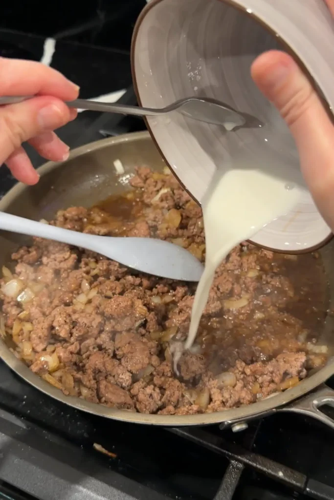 Cornstarch slurry being poured into honey ground beef to thicken the sauce.