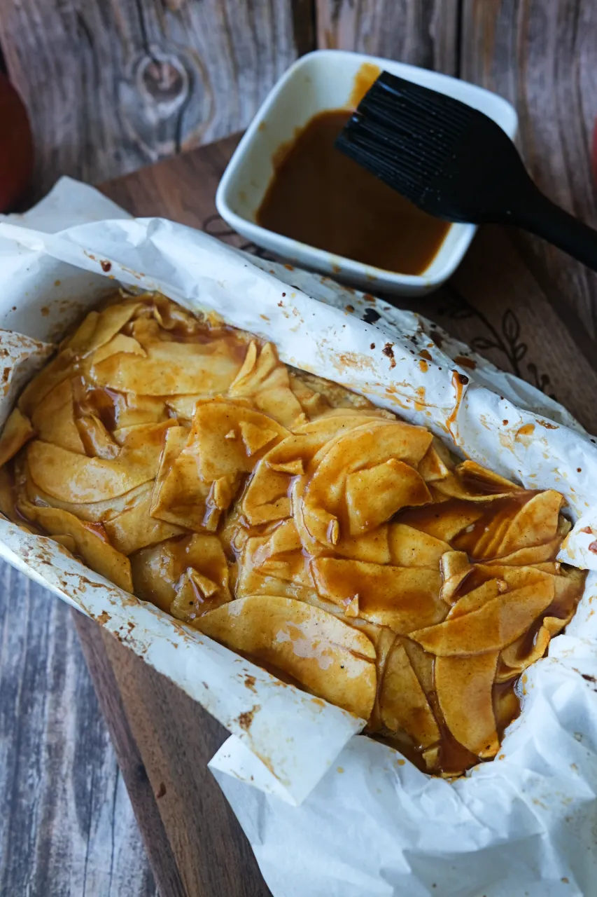 Close-up of invisible apple cake topped with caramel sauce and thinly sliced apples.