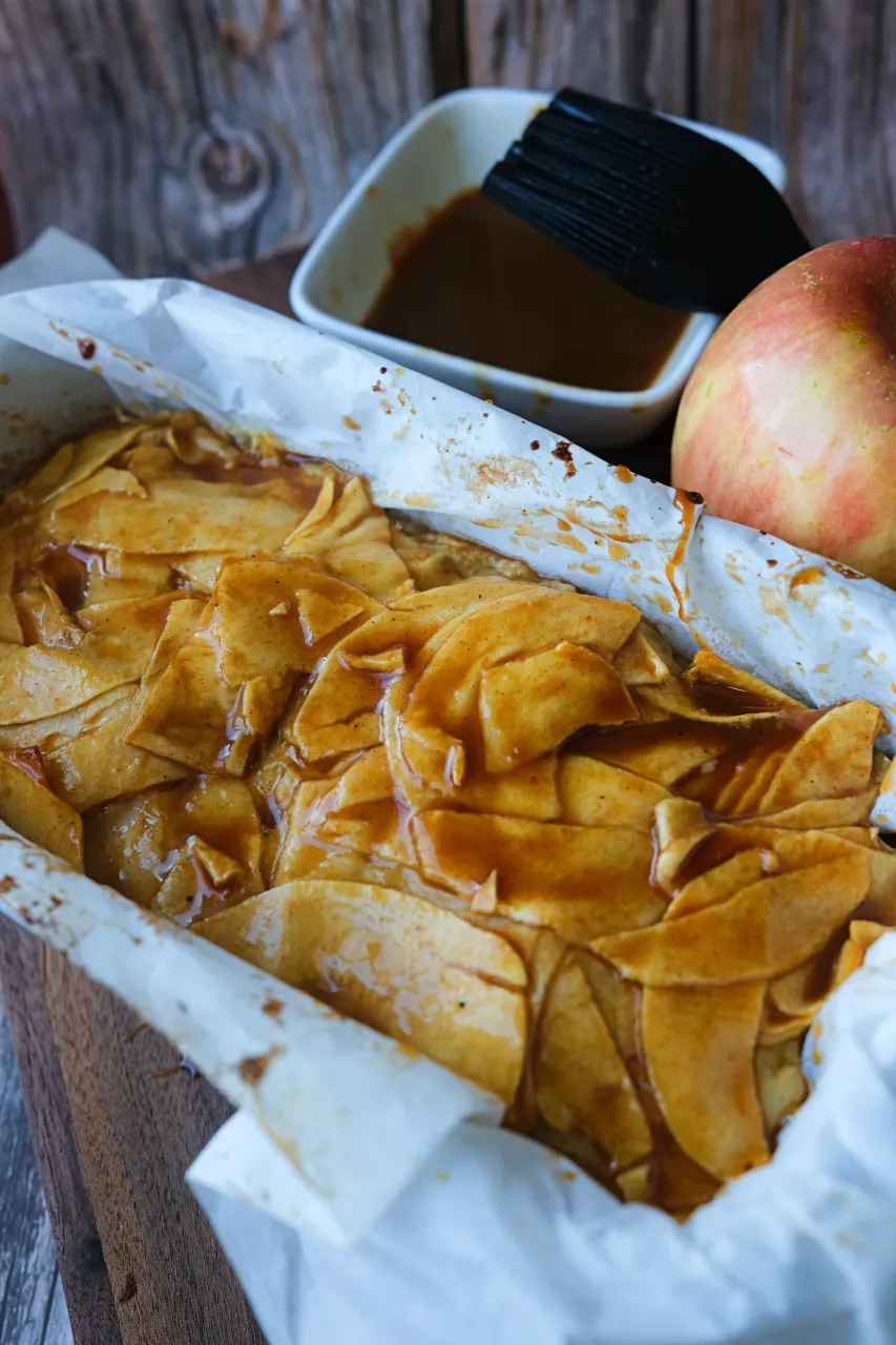 Invisible apple cake in a parchment-lined loaf pan brushed with caramel sauce.