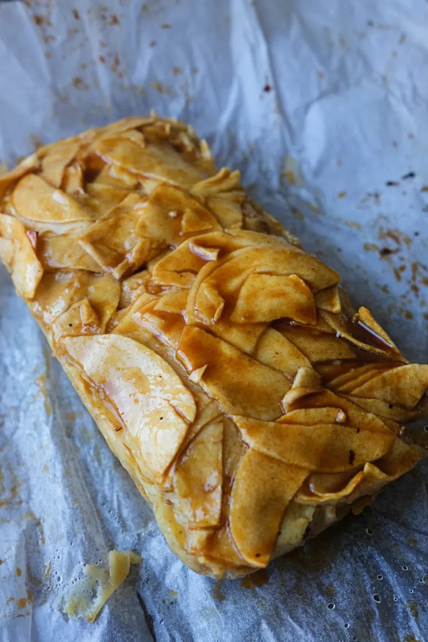 Freshly baked invisible apple cake removed from the loaf pan and topped with caramel.