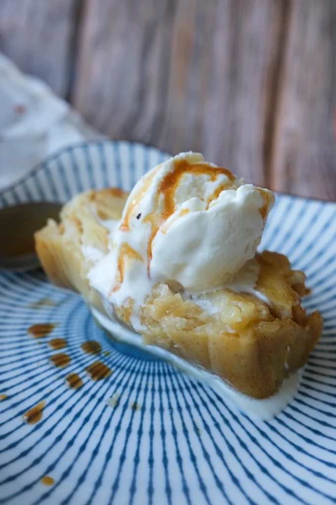 Slice of invisible apple cake served with vanilla ice cream and caramel sauce.