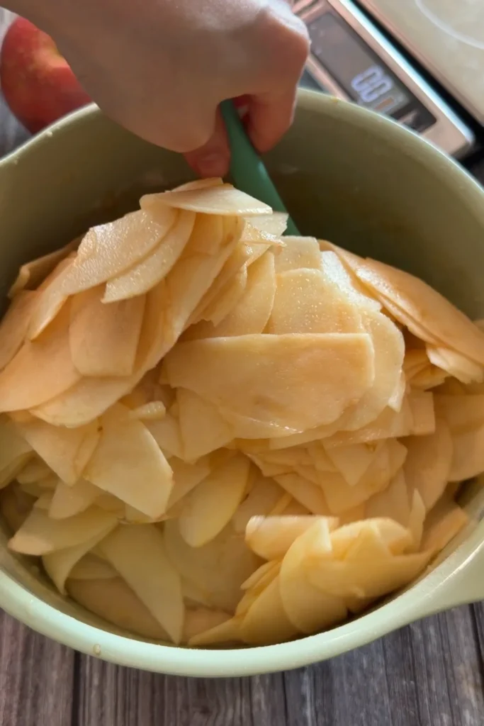 Thinly sliced apples being folded into the invisible apple cake batter.
