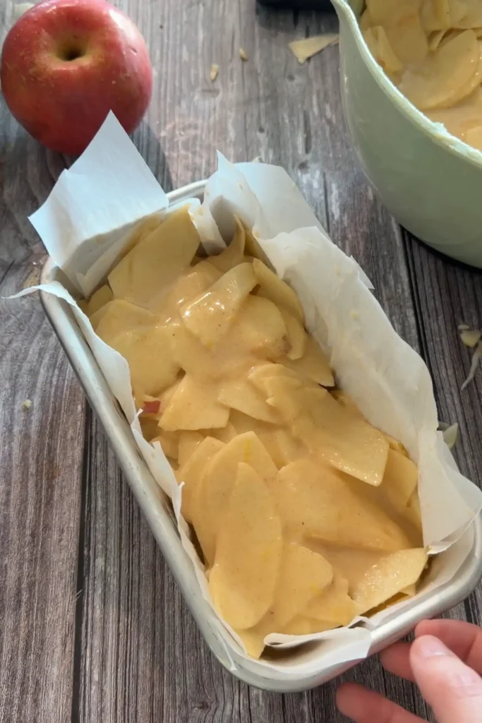 Invisible apple cake mixture packed into a parchment-lined loaf pan before baking.